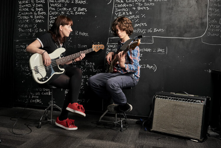 Instructor and student taking bass guitar lessons for kids