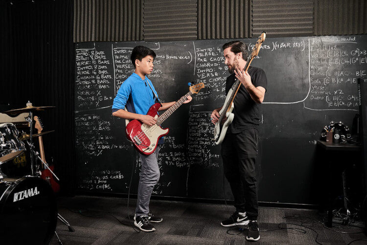 Instructor and student taking advanced bass guitar lessons