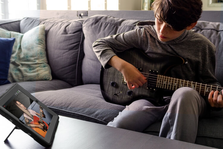 boy at home using iPad for video guitar lesson