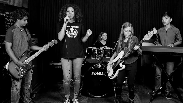 School of Rock students play music on stage and in a band in our music programs