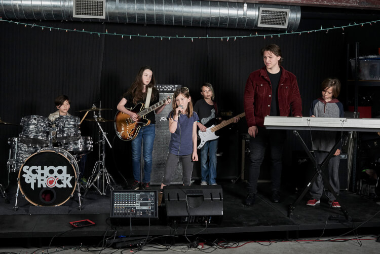 Students playing onstage in the rock 101 music program for kids